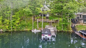 Una casa flotante amarrada en un muelle, rodeada de un bosque denso.