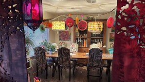 A dining area with a wooden table, floral chairs, and a colorful rug.