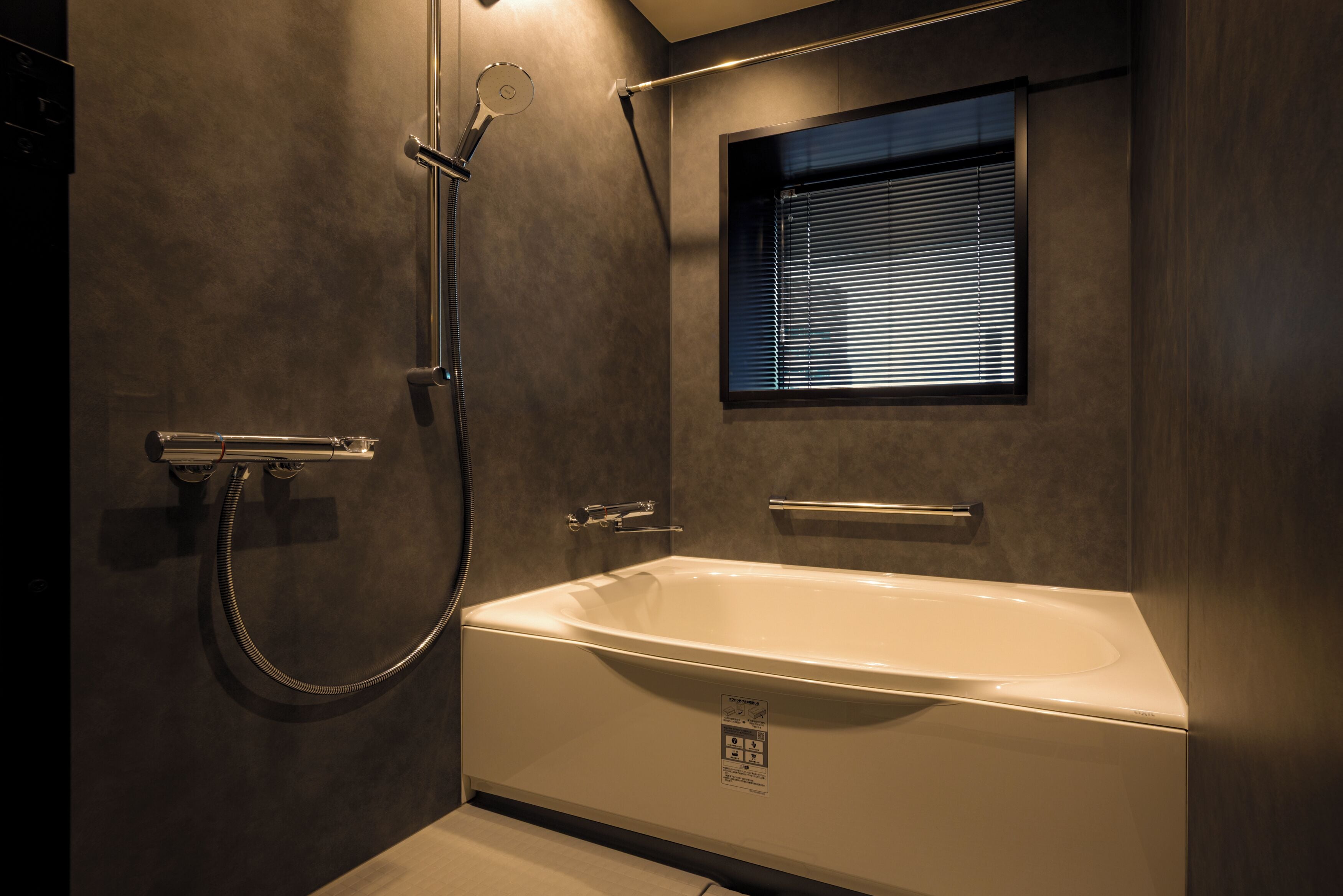 A modern bathroom with a bathtub, shower, and window.