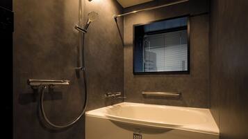 A modern bathroom with a bathtub, shower, and window.