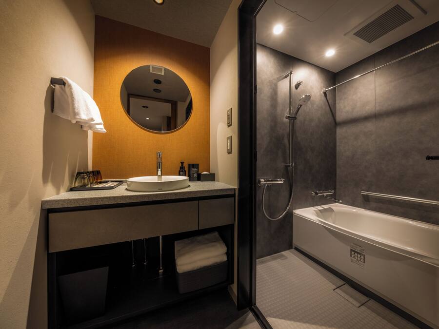 A modern bathroom with a round mirror, a sink, and a walk-in shower.