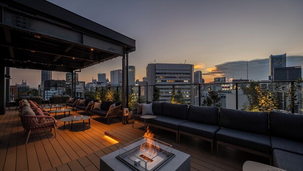 A rooftop terrace with a fire pit, seating area, and city skyline views. - &Here SHINJUKU (Tokyo)