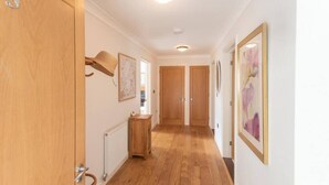 A hallway with wooden flooring, a radiator, a small wooden table, and framed artwork on the walls. - Modern 2-Bed Flat in Tavistock Centre (Tavistock)