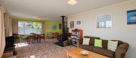 Una sala de estar acogedora con un sofá, una mesa de centro y una chimenea. Hay un comedor con una mesa y sillas, y una estantería llena de libros.