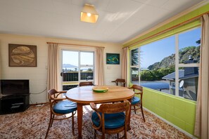 Ein Essbereich mit einem runden Tisch, sechs Stühlen, einem Fernseher und Blick auf einen Hügel.