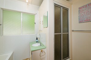 Ein Badezimmer mit einem grünen Waschbecken, einem Spiegel und einem Milchglasfenster.