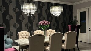 Zona pranzo con tavolo e sedie, un lampadario e carta da parati decorata.