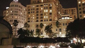 A multi-story hotel with illuminated windows and a dome on the left. - Waterfront Downtown West Palm Beach with  Luxury Amenities (West Palm Beach)