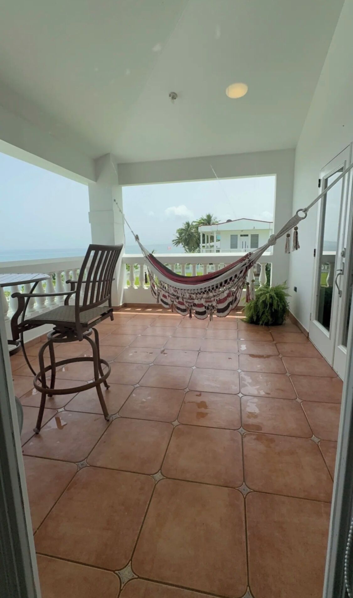 Un balcon avec un hamac, une table et des chaises.