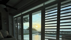 Quarto com grande porta de vidro deslizante para vista da água, sofá e ventilador de teto.