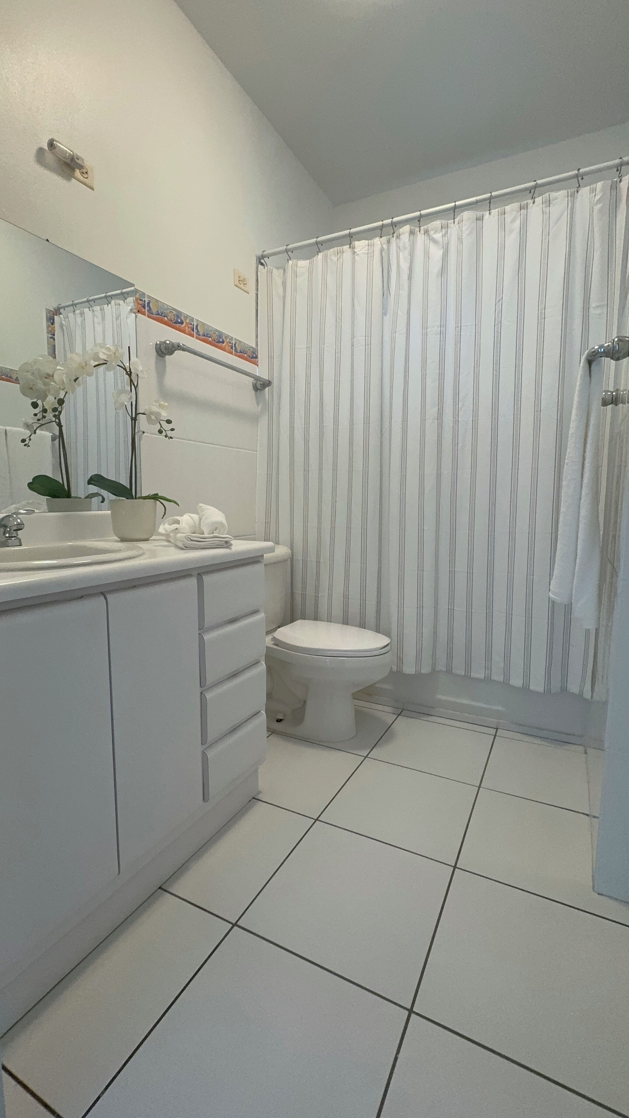 A bathroom with a white sink, toilet, and shower curtain.