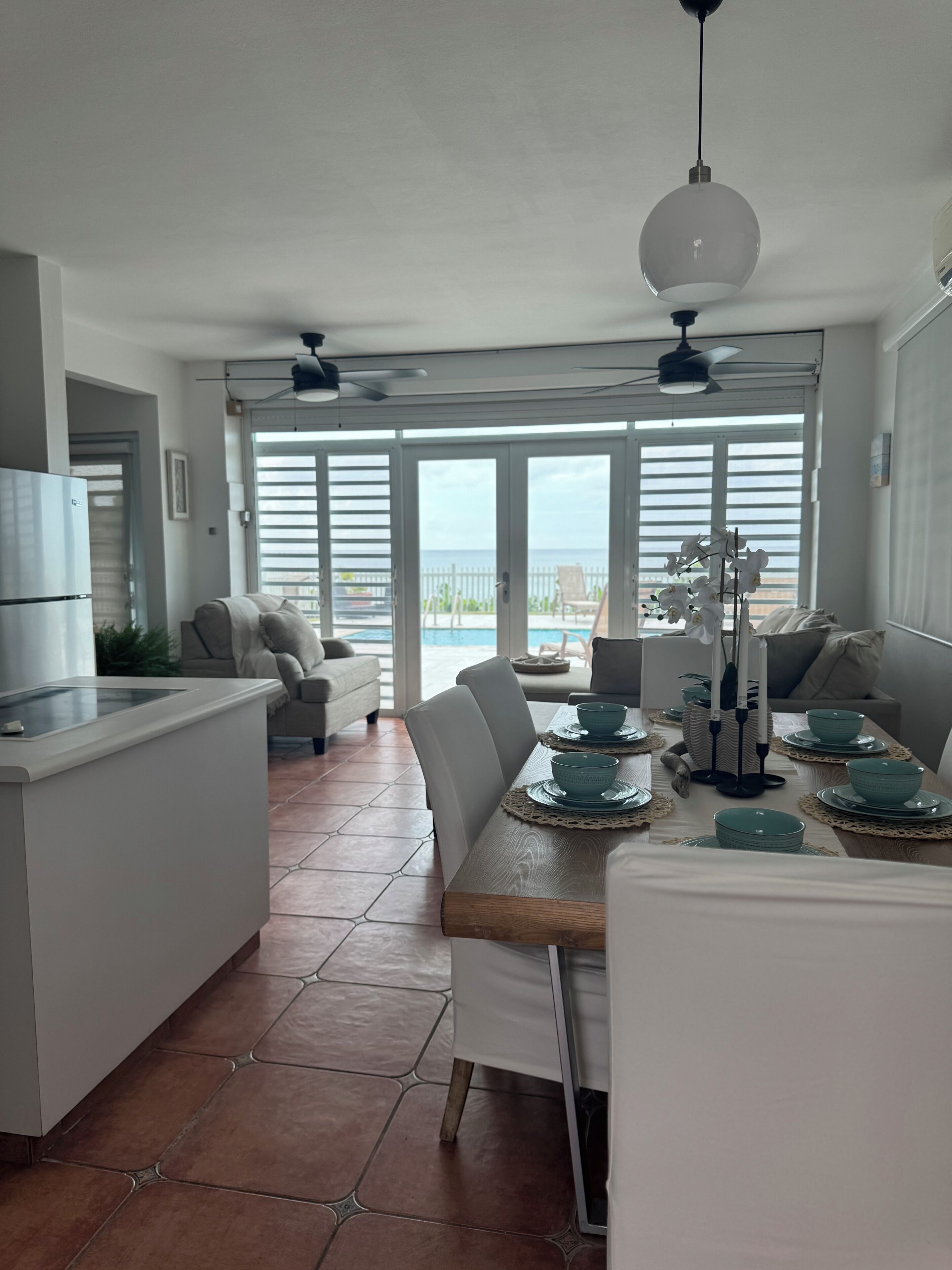 Una cocina moderna con comedor, ventanas amplias y vista al mar.