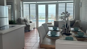 Uma cozinha moderna com área de jantar, janelas amplas e vista para o mar.