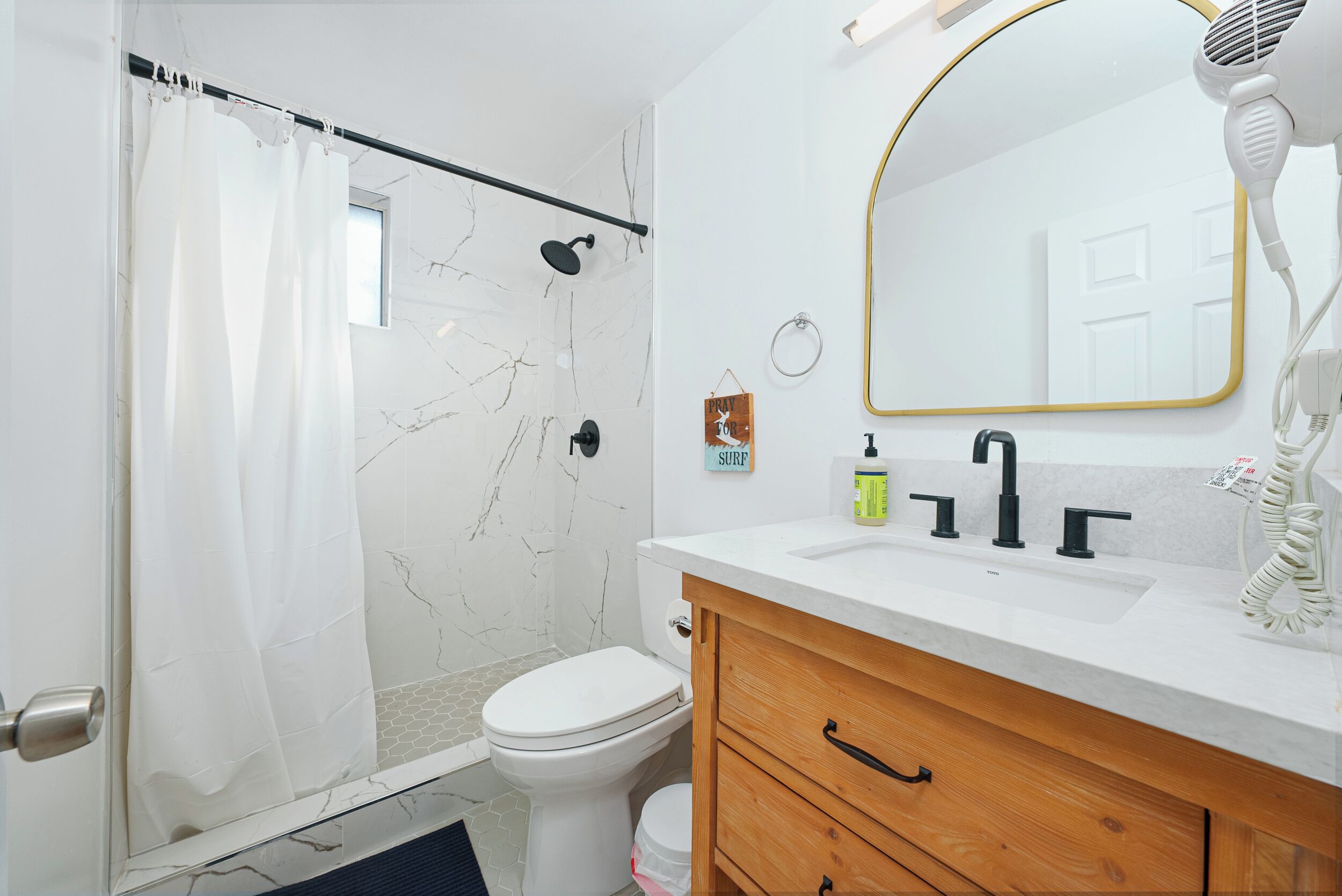 Ein Badezimmer mit Dusche, Toilette, Waschtisch und Spiegel.