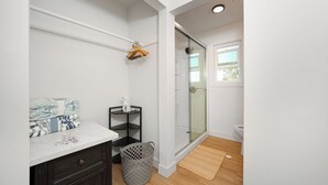 Un baño con cabina de ducha de vidrio, un lavabo blanco y un mueble de madera oscura.