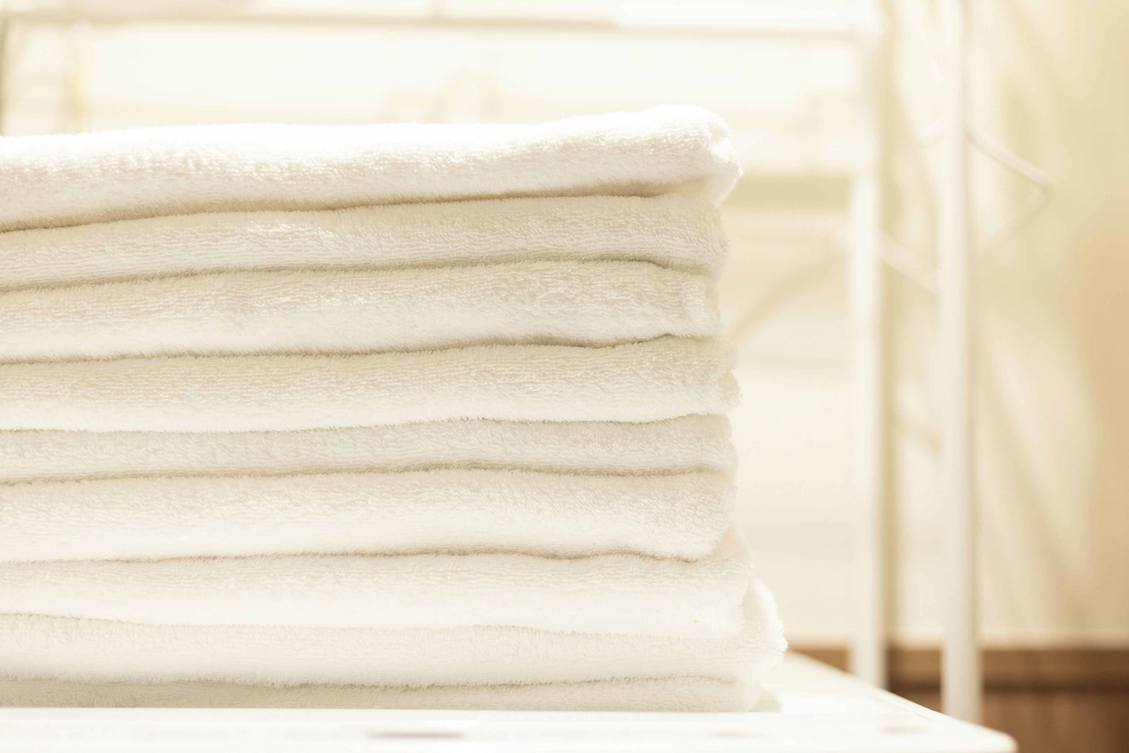 Une pile de serviettes blanches sur une surface blanche.