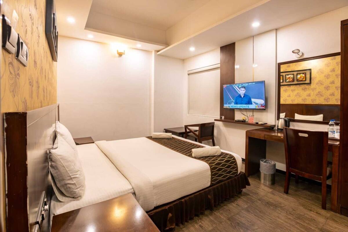 Une chambre d’hôtel équipée d’un lit, d’un bureau, d’une chaise, d’une télévision et d’une poubelle.