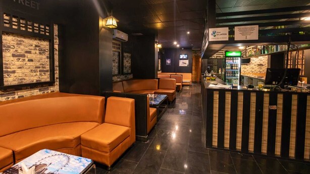 Zona de bar moderna con asientos de cuero y una barra que exhibe diversas bebidas.