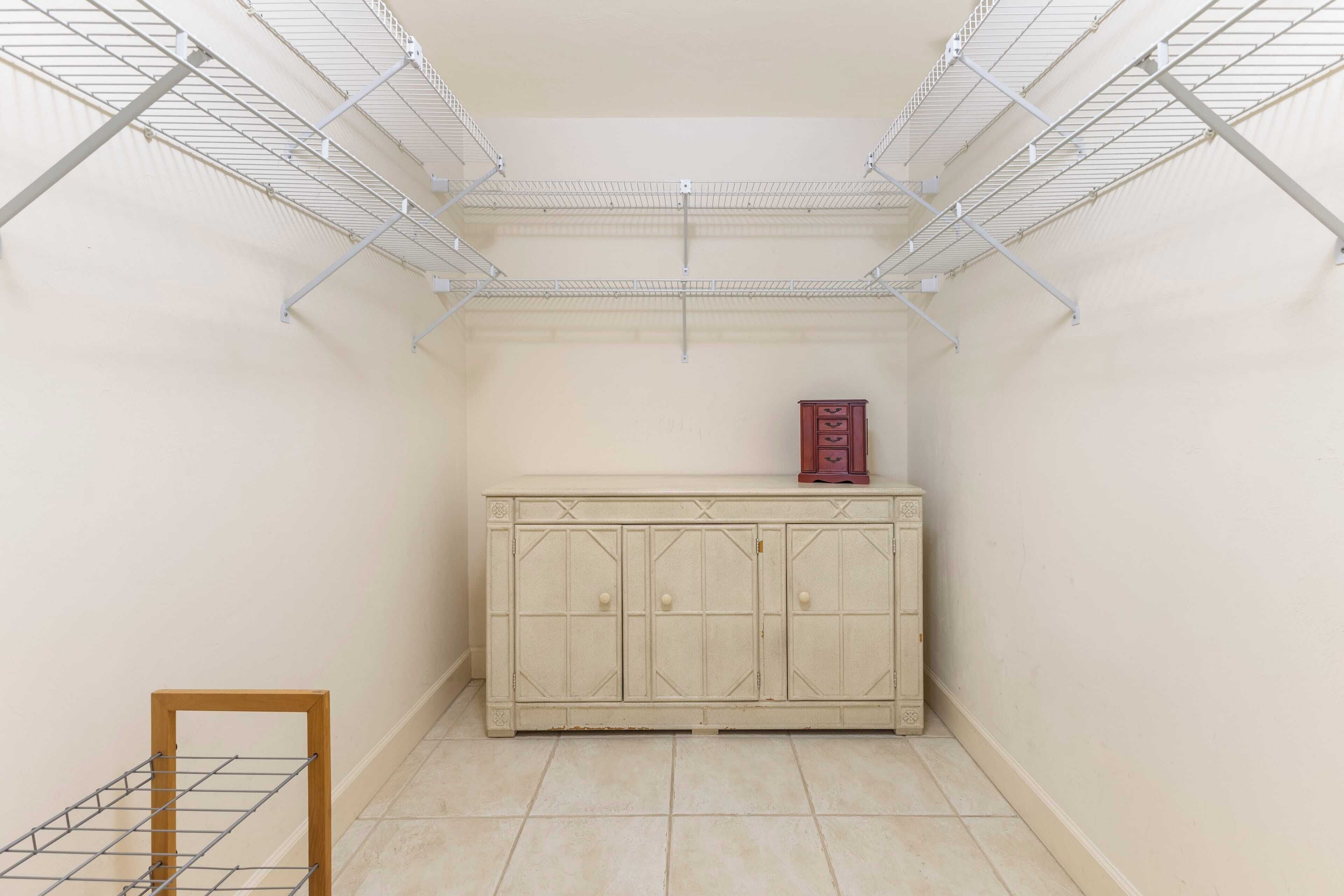 Une petite pièce fermée, avec une armoire blanche et un étendoir à linge en métal.