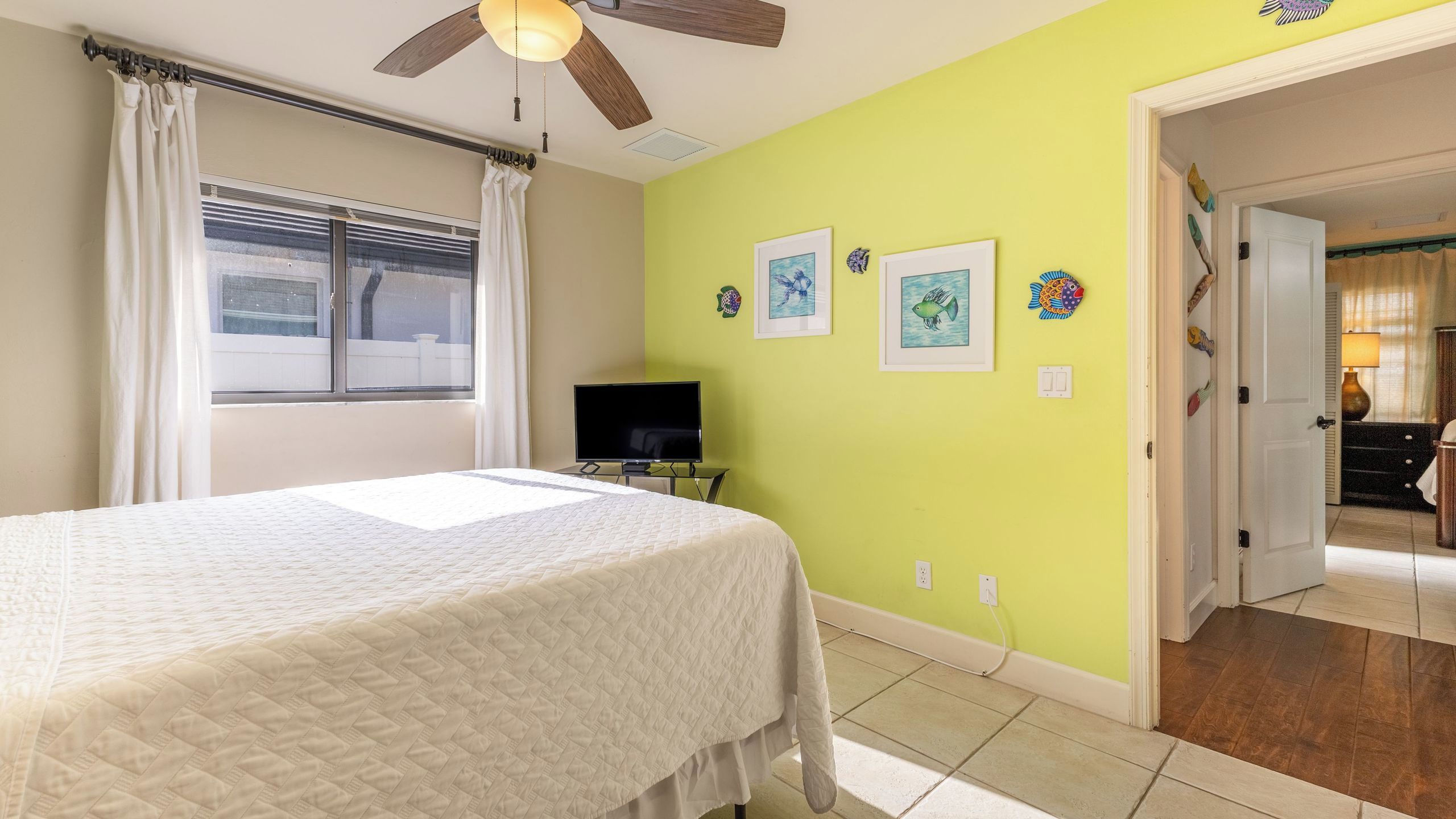 A bedroom with a bed, a television, and artwork on the wall.