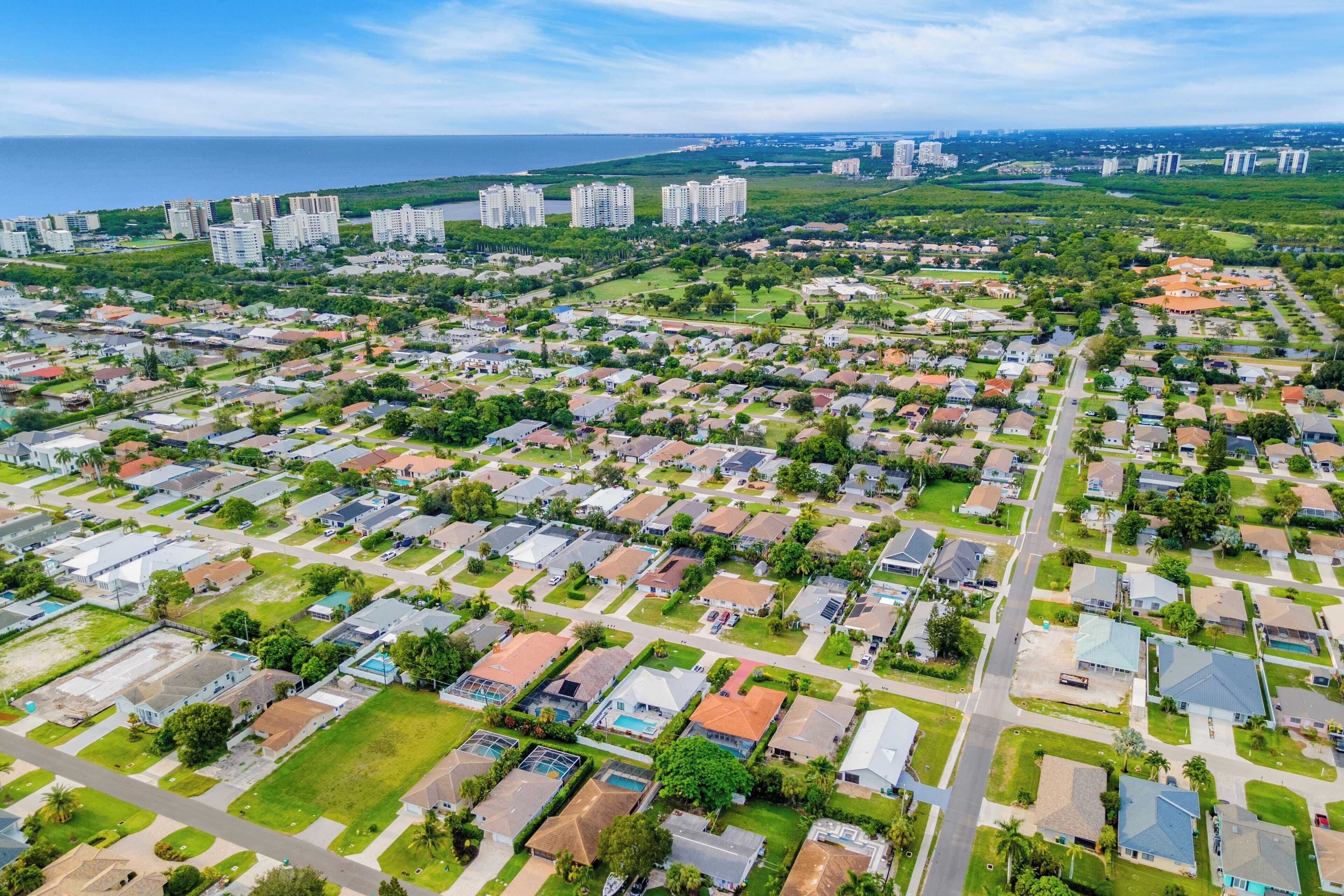 Vue aérienne d’un quartier résidentiel avec de nombreux immeubles de grande hauteur, des espaces verts et une côte en arrière-plan.