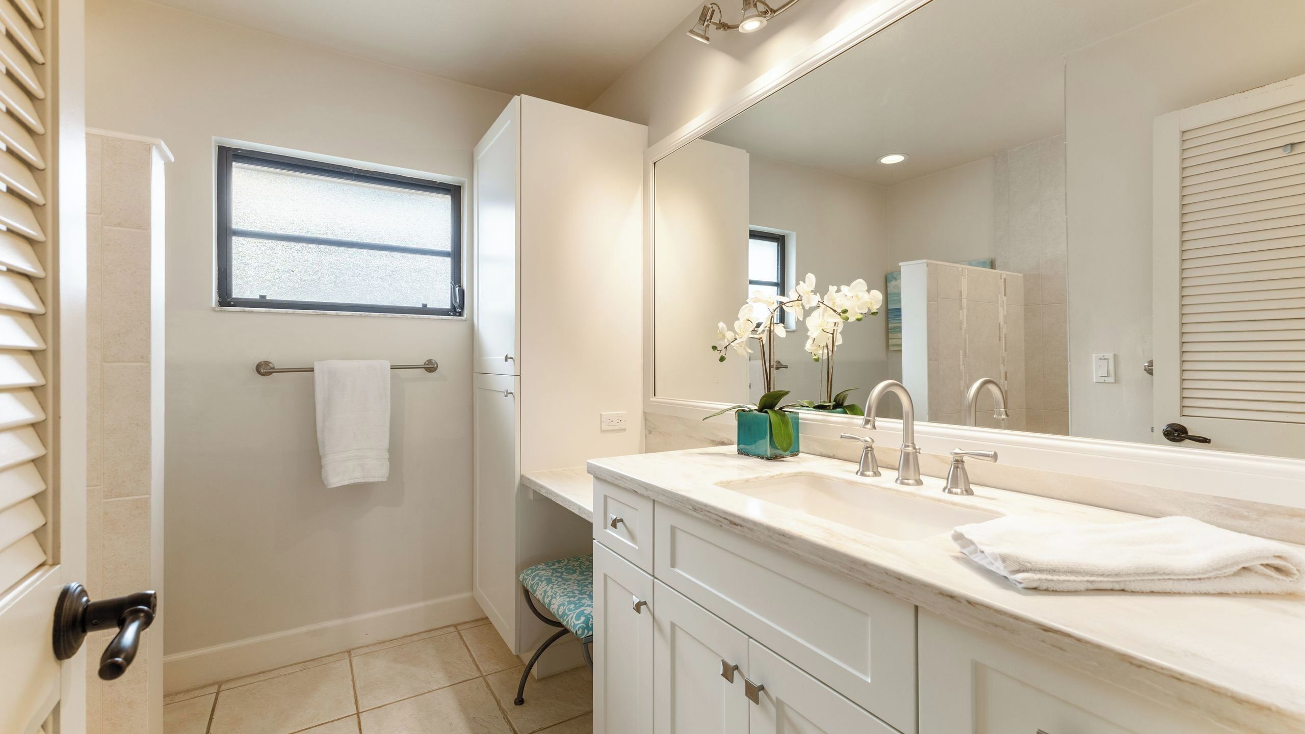 A bathroom with a double sink, a mirror, a towel rack, and a window.