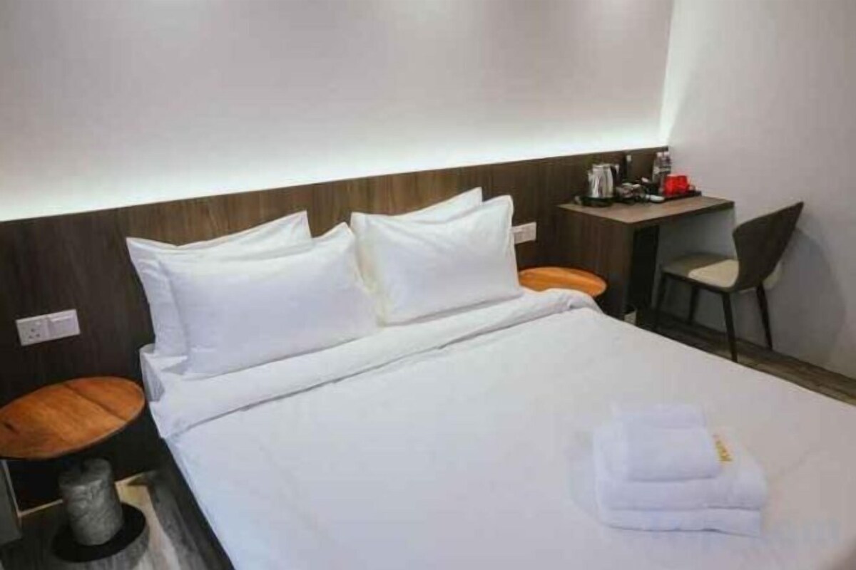 A hotel room with a bed, a desk, and a chair.