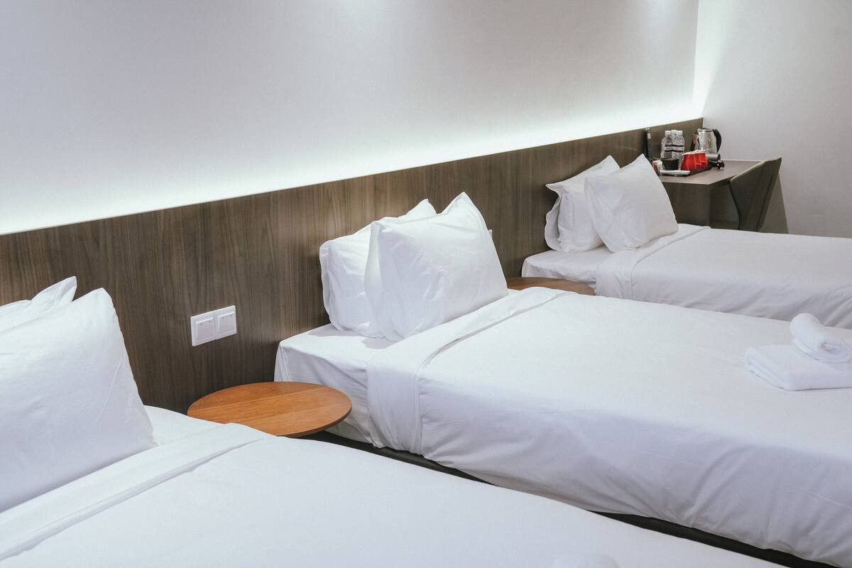 A hotel room with two single beds, a wooden side table, and a small round table.