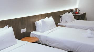 A hotel room with two single beds, a wooden side table, and a small round table.