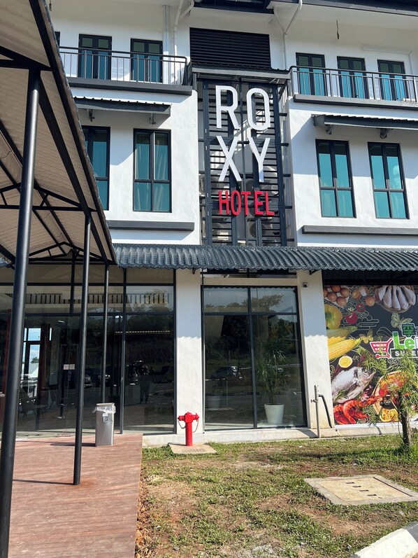 A hotel with a prominent sign reading "ROYX HOTEL" and a large mural of food items on the facade.