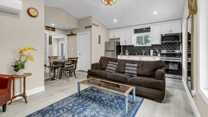 A modern living room with a brown sofa, a glass coffee table, and a blue rug.