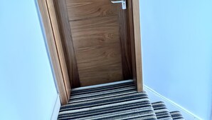 A wooden door with a metal handle and a keyhole, leading to a staircase with a striped carpet. - London Studio Retreat - Colney Hatch Lane (London)