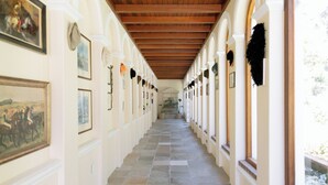 A corridor with a tiled floor, white walls, and wooden ceiling beams. - Manor House at La Roche Estate - Franschhoek (Franschhoek)
