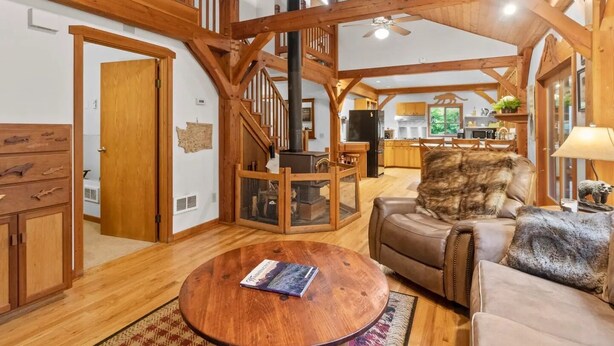 Un salón amplio con vigas de madera, una chimenea, zona de comedor y cocina.