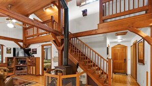 Un amplio salón con una escalera de madera, una chimenea y un televisor.