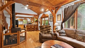 Interior acogedor de una cabaña con paredes de madera, chimenea, sofá y comedor.