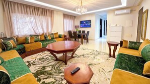 A spacious living room with a large sofa set, a coffee table, and a dining area. - Luxoria home - 2 min to corniche (Tangier)