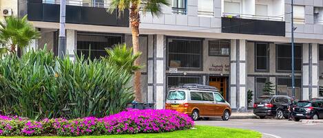 A modern building with a sign reading "RESIDENCE YAS" and a van parked in front.