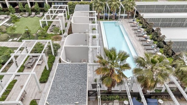 An aerial view of a hotel with a swimming pool, lounge areas, and a landscaped garden. - luxury apartment with water views. Walking distance from beach (Port Melbourne)