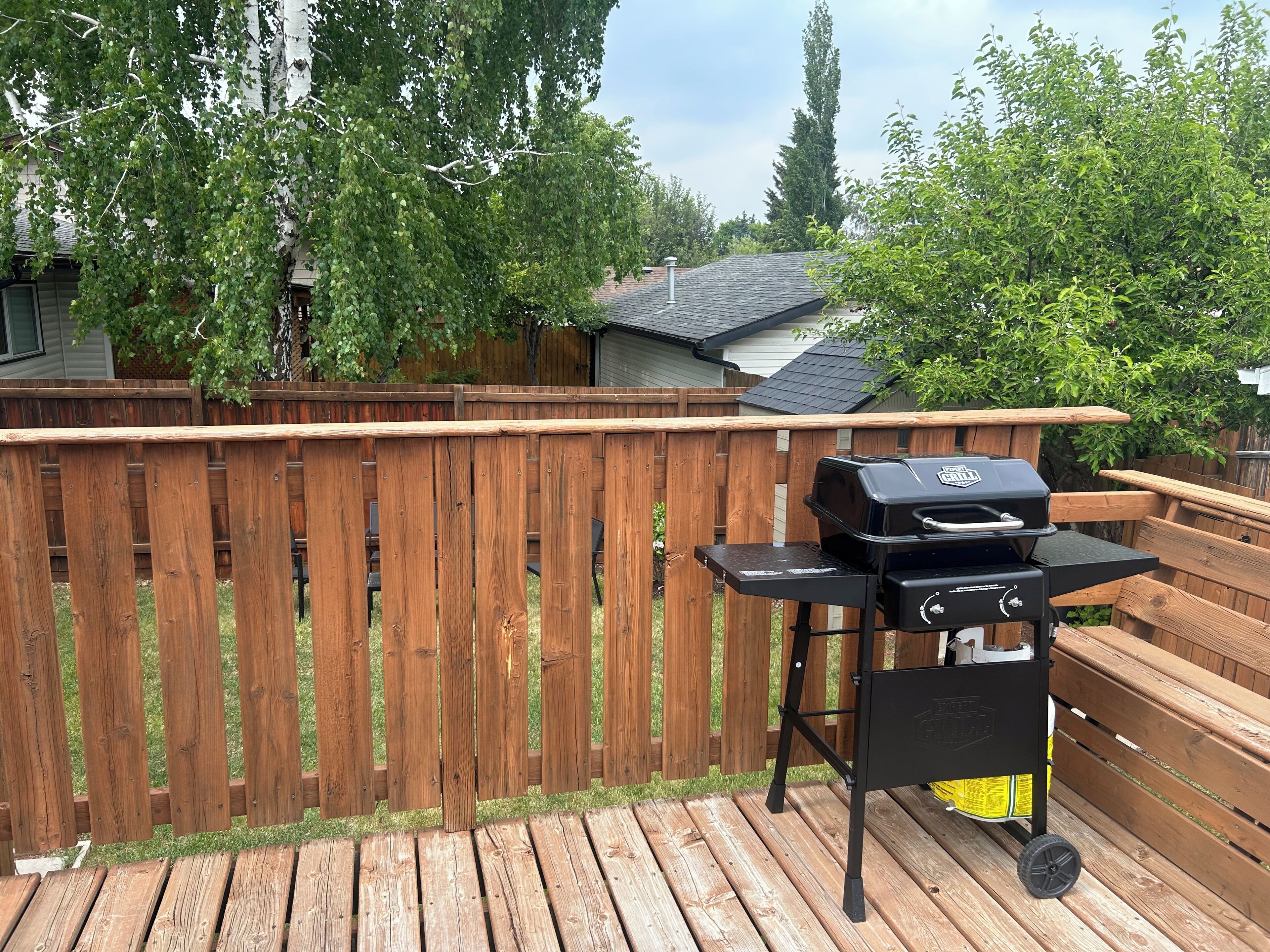 A wooden deck with a barbecue grill and a wooden table.