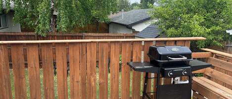 A wooden deck with a barbecue grill and a wooden table.
