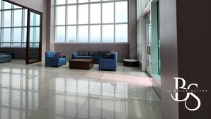 Una habitación amplia con ventanas grandes, un sofá azul y una mesa de centro de madera.