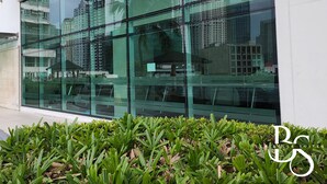 Un edificio moderno con amplios ventanales de vidrio que reflejan edificios altos circundantes y grúas de construcción.
