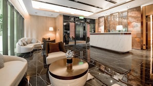 Eine moderne Lobby mit einer Rezeption, einer Sitzecke und einer großen Pflanzengruppe als Blickfang.