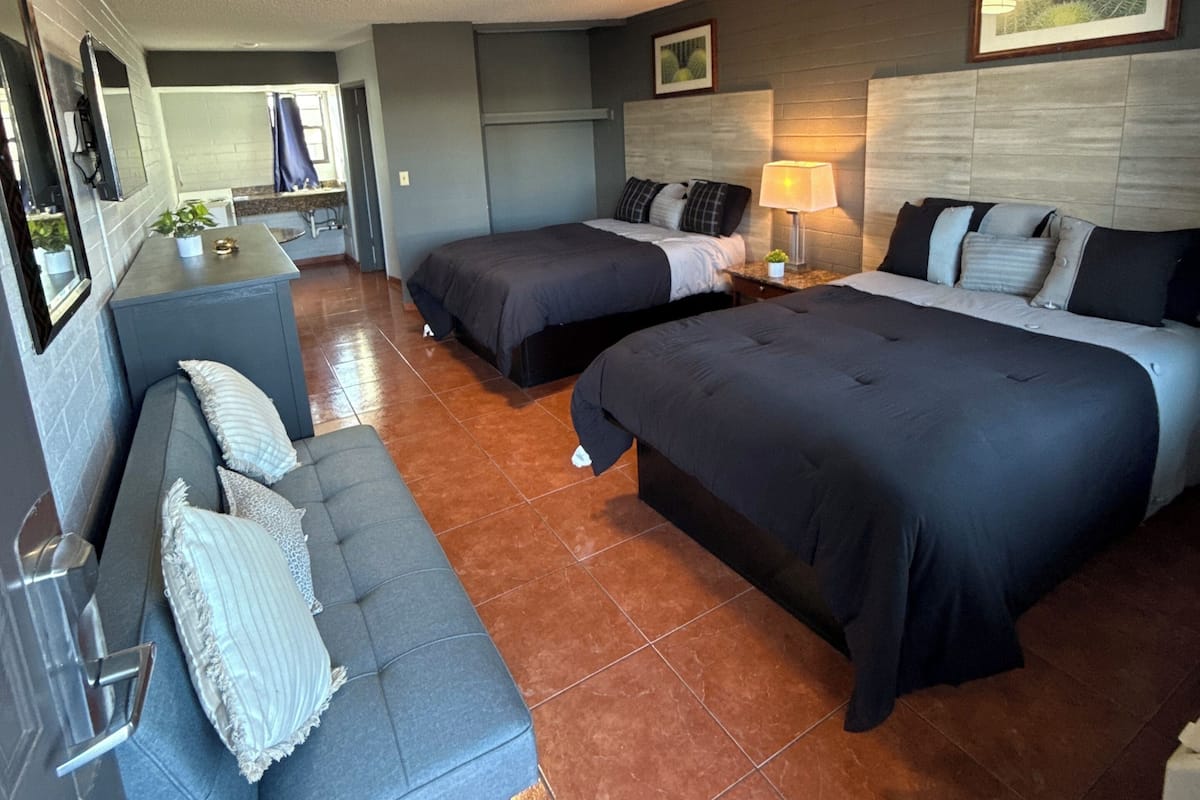 Une chambre d’hôtel avec deux lits, un canapé, un petit coin cuisine et une salle de bain.