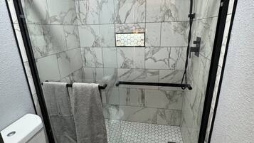 Ein Badezimmer mit Duschkabine, Toilette und Fliesenboden mit Sechseckfliesen.