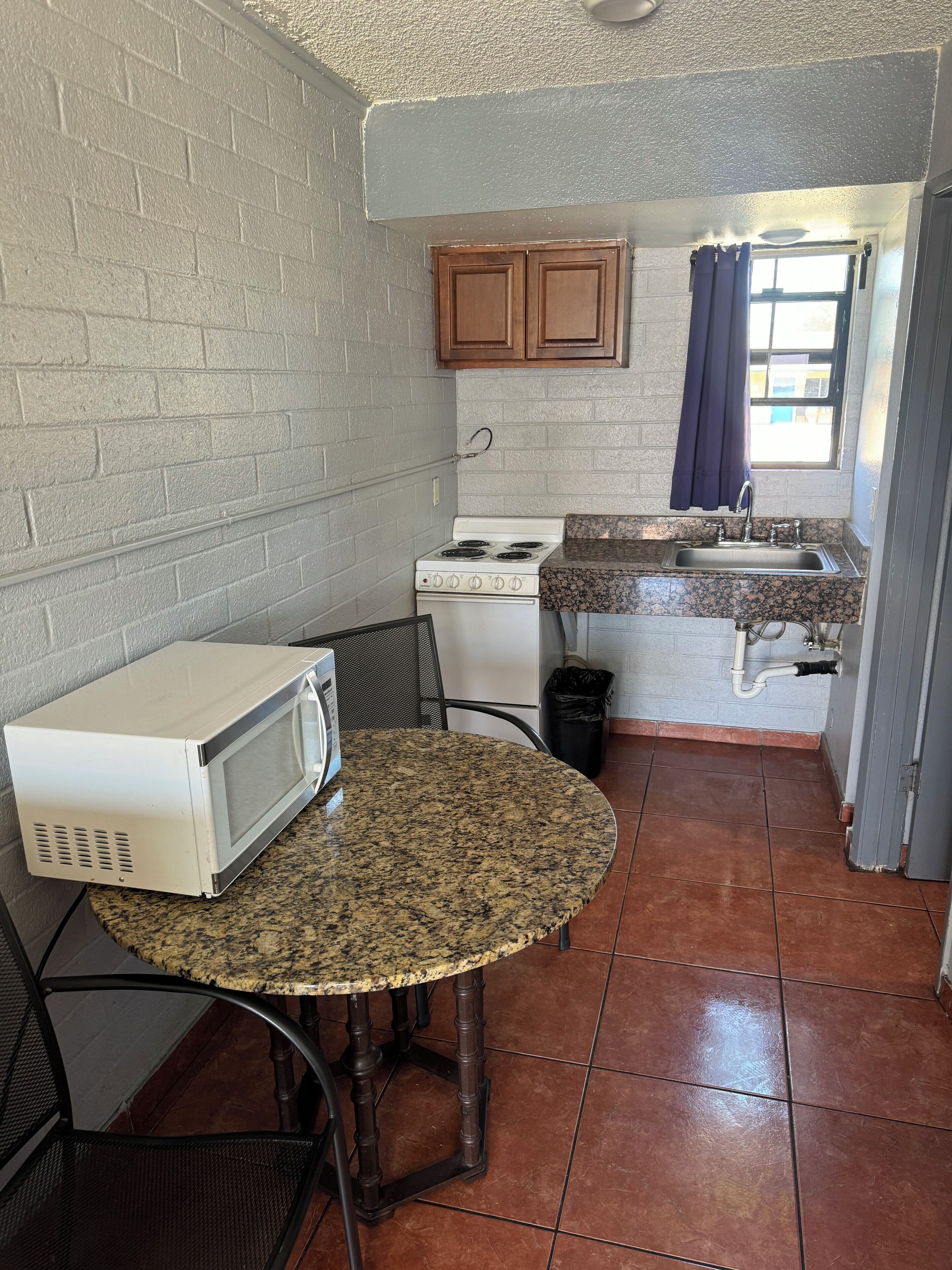 A compact kitchen with a stove, microwave, and sink.