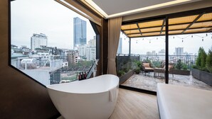 A modern bathroom with a freestanding bathtub, large windows, and a view of the cityscape. - iRest Signature Ba Dinh Lakeside (Hanoi)