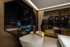 Une salle de bain moderne dotée d’une grande baignoire, d’une douche à parois de verre et offrant une vue sur la ville.