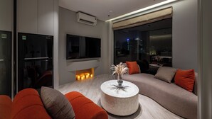 A modern living room with a sofa, a round coffee table, and a flat-screen TV mounted on the wall. - iRest Signature Ba Dinh Lakeside (Hanoi)